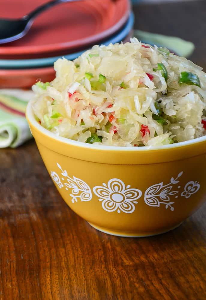 A table set for a summer gathering, with a bowl of sauerkraut coleslaw as one of the dishes.