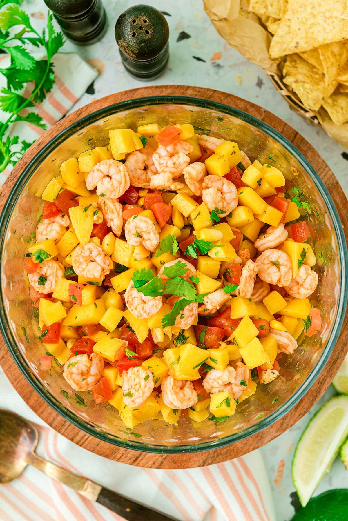 Overhead view of several Spicy Shrimp Gyros with Mango Salsa arranged on a platter, surrounded by fresh ingredients like mangoes, cilantro, and limes