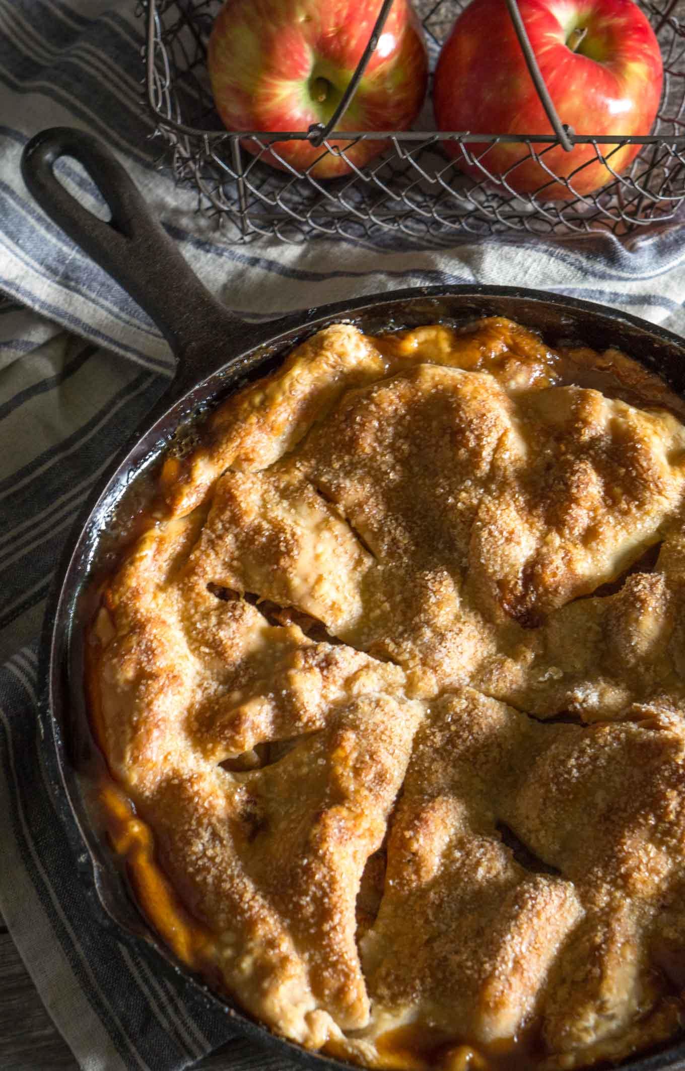 A close-up shot of a golden-brown apple pie with a flaky crust, showing steam gently rising from the filling.
