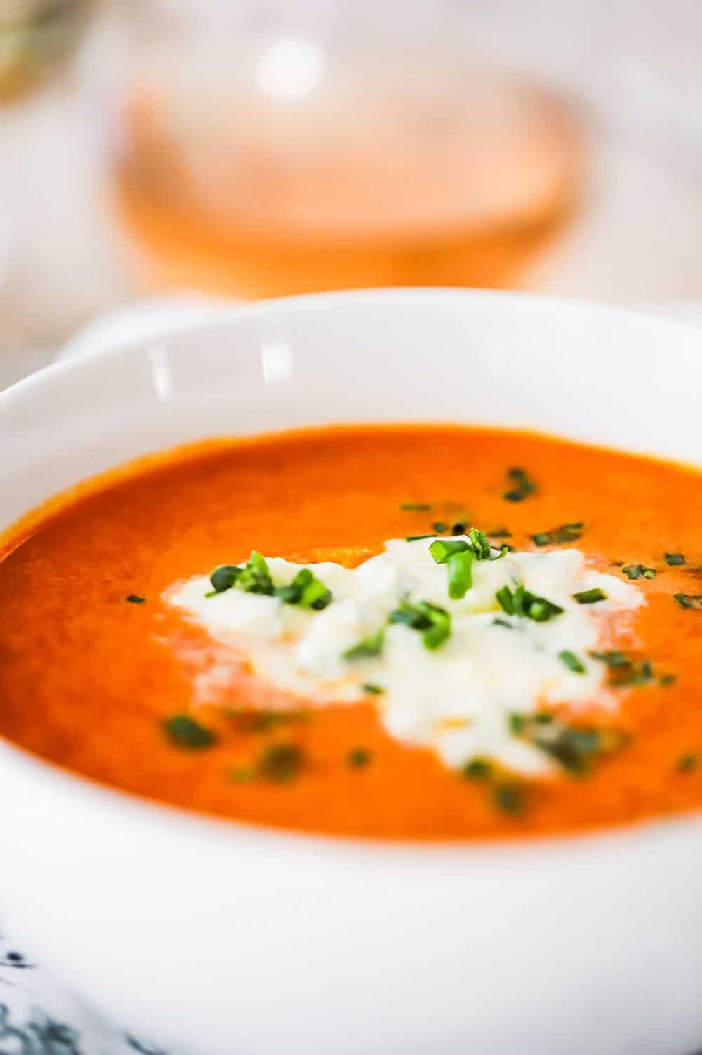 Close-up shot of a bowl of chilled carrot and ginger soup with fresh herbs