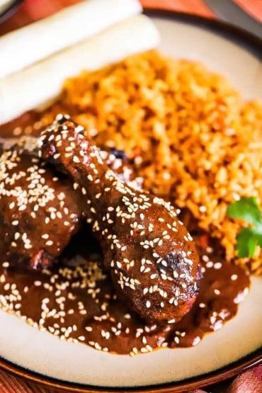 close-up shot of fried chicken being smothered in mole poblano sauce