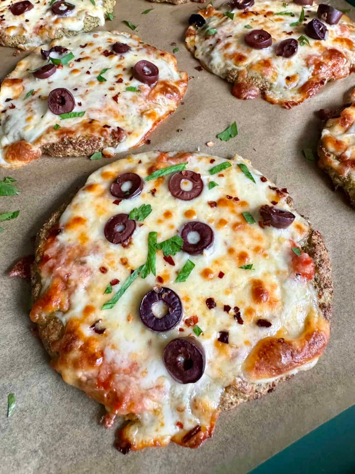 Close-up shot of four mini pizzas with broccoli on a rustic wooden table