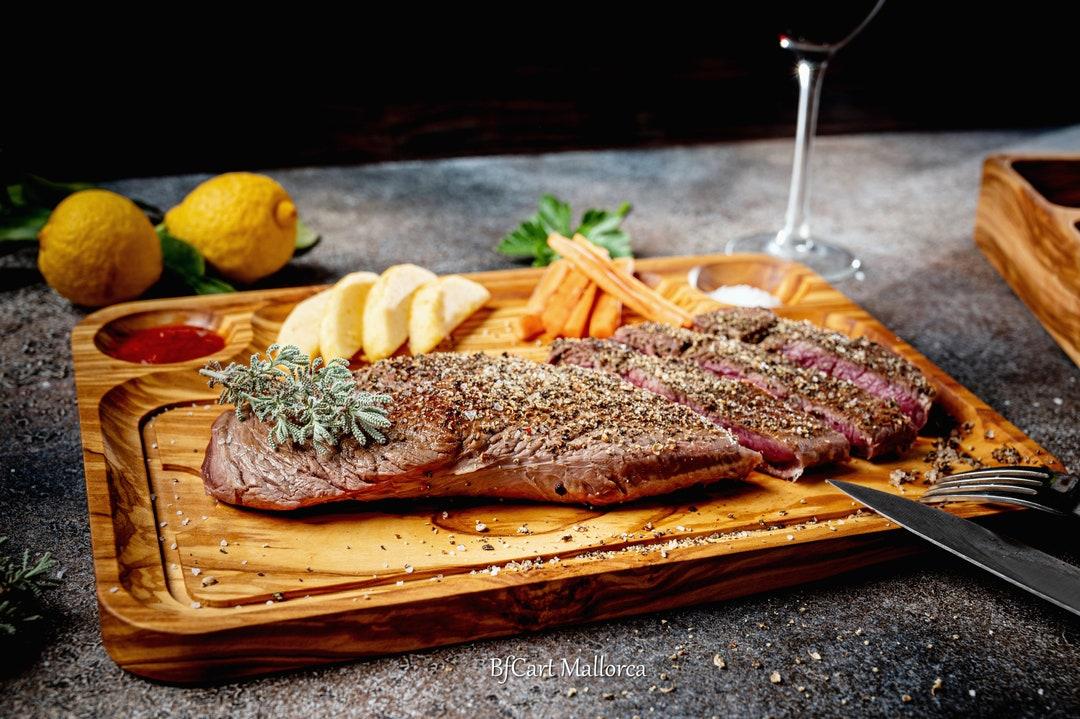 A rustic wooden table set with various ingredients for making the Steak & Cheese Sub, including steak, cheese, onions, peppers, bread, etc.