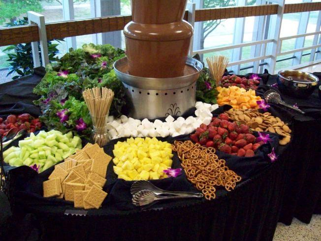 A beautifully styled table setting with the Key Lime Chocolate Fondue as the centerpiece, surrounded by fresh fruit, cookies, and other dippers.
