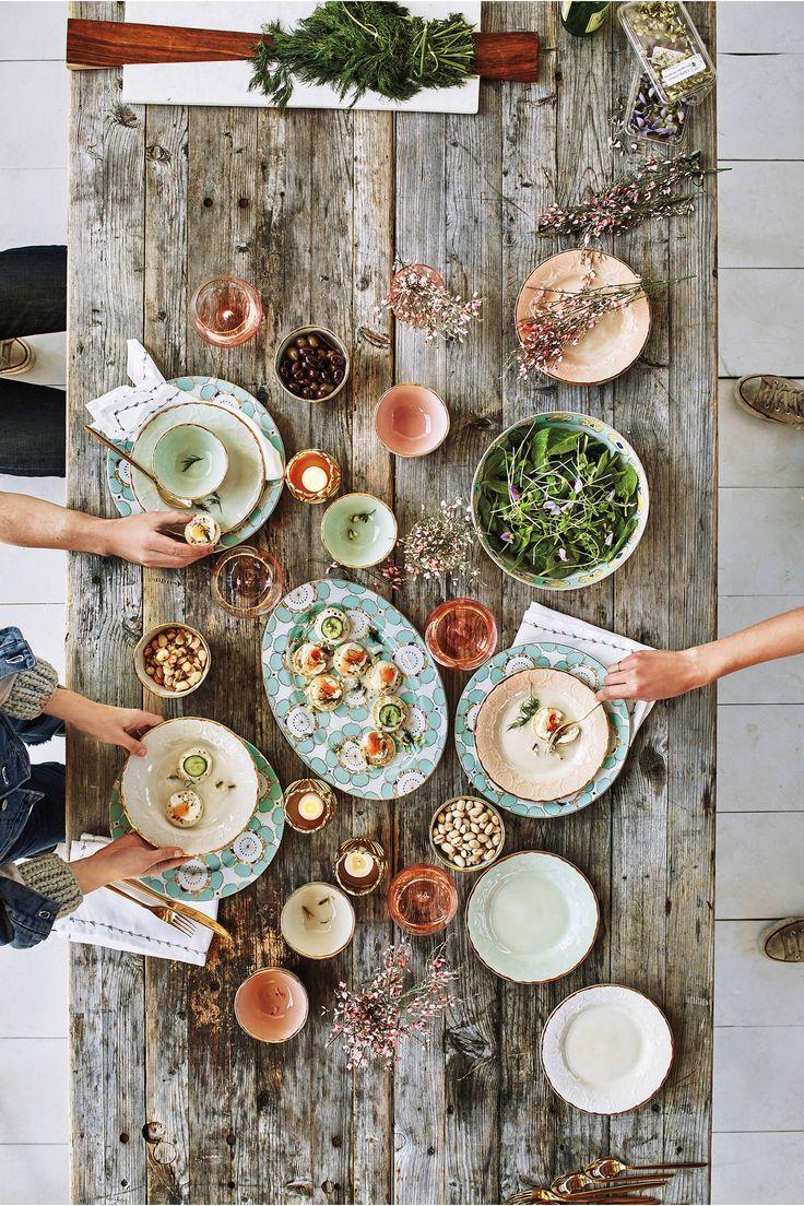 A rustic wooden table set with a plate of lingonberry tartlets, a steaming cup of tea, and a bowl of fresh lingonberries.