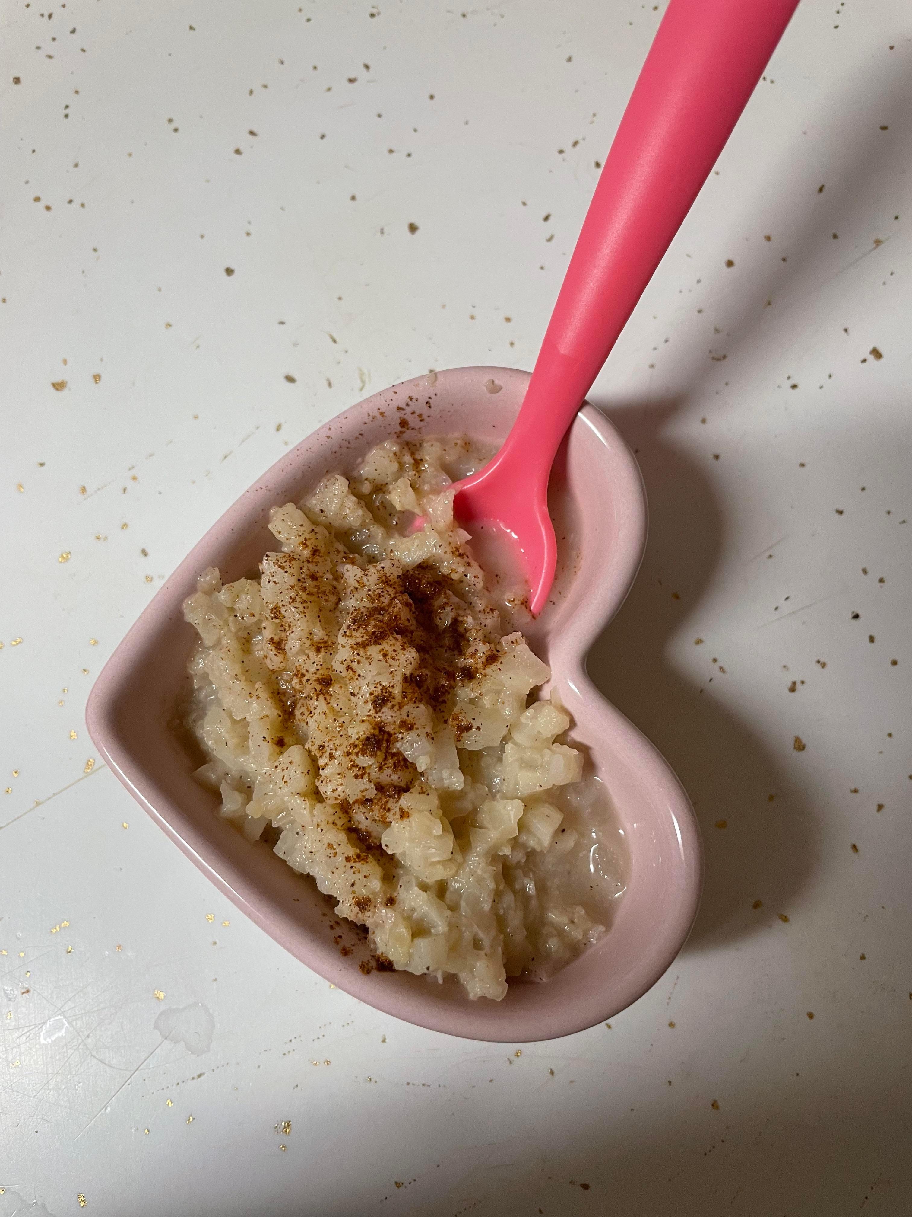 A person spooning cauliflower rice pudding into a bowl