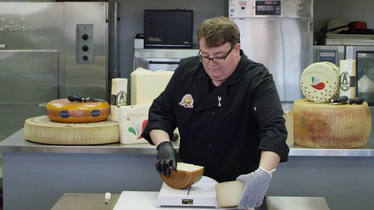 Close-up of a person slicing a wheel of smoked Manchego cheese