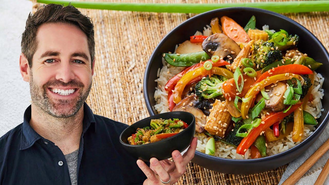 A person happily enjoying a plate of vegetable stir-fry
