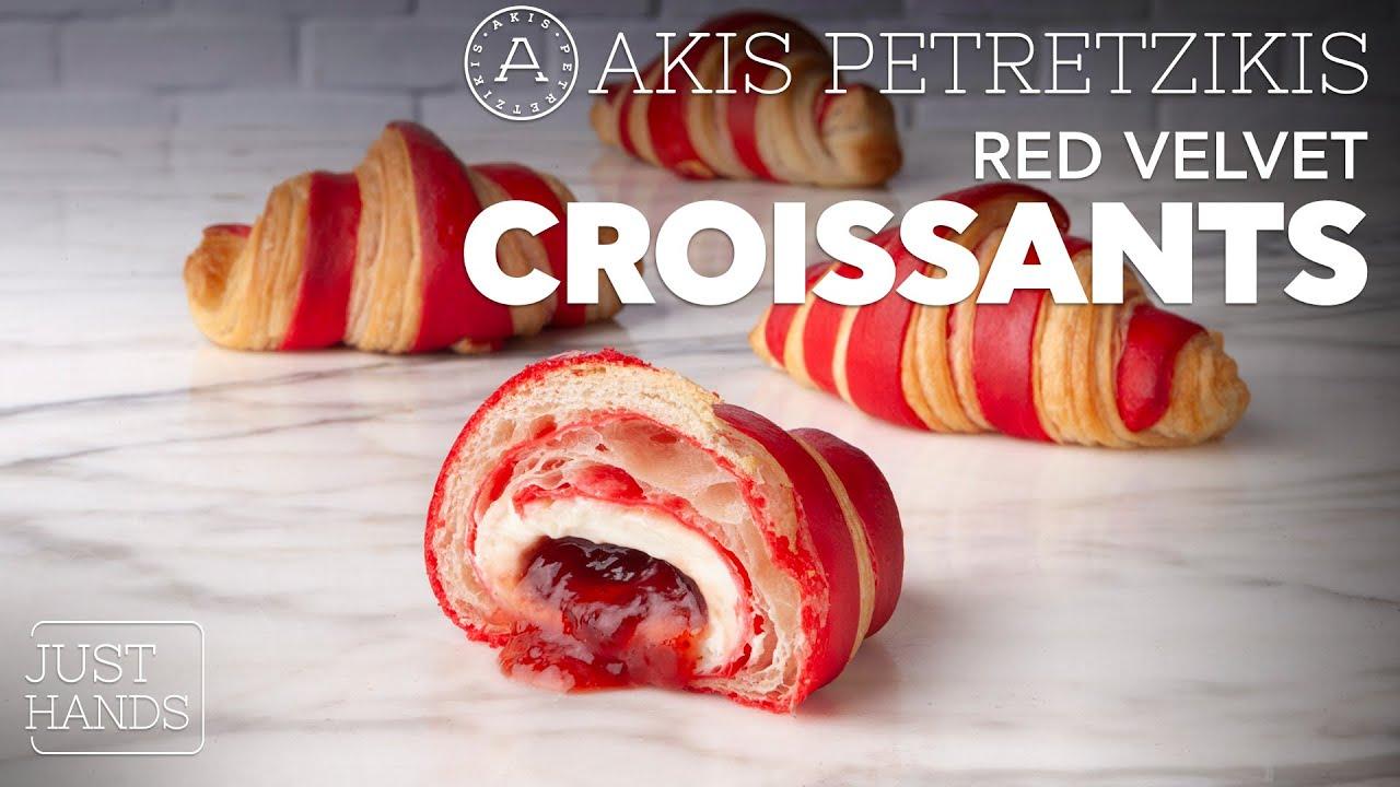 A rustic kitchen setting with a plate of freshly baked red velvet croissants and a bowl of cream cheese frosting