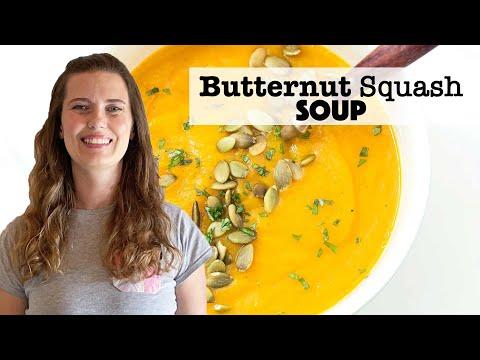A person smiling while holding a bowl of butternut squash soup