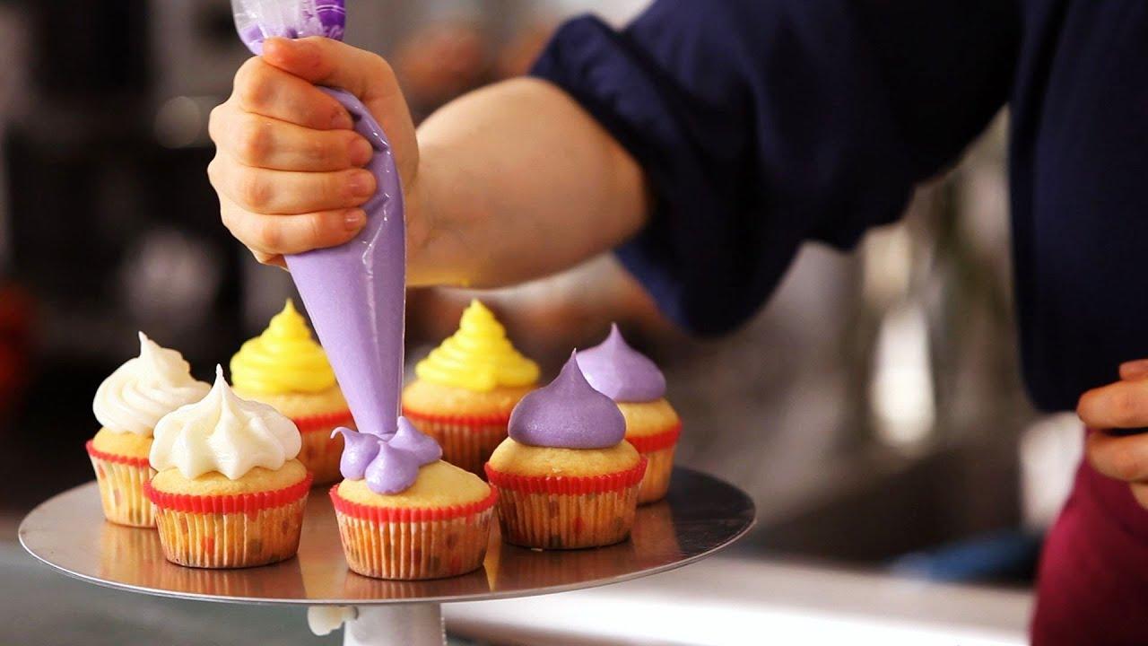 A person decorating cupcakes with frosting