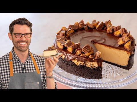 A person smiling and holding a slice of peanut butter cheesecake