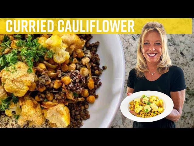 A person enjoying a bowl of curried cauliflower and chickpeas outdoors