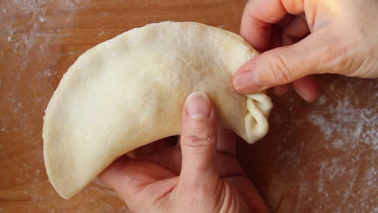 Hands shaping empanada dough