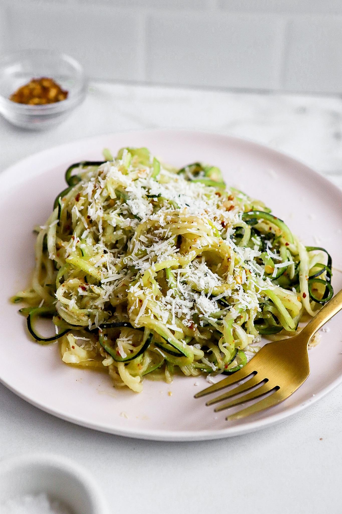 Person enjoying a plate of keto zucchini noodles with lamb and mint sauce outdoors