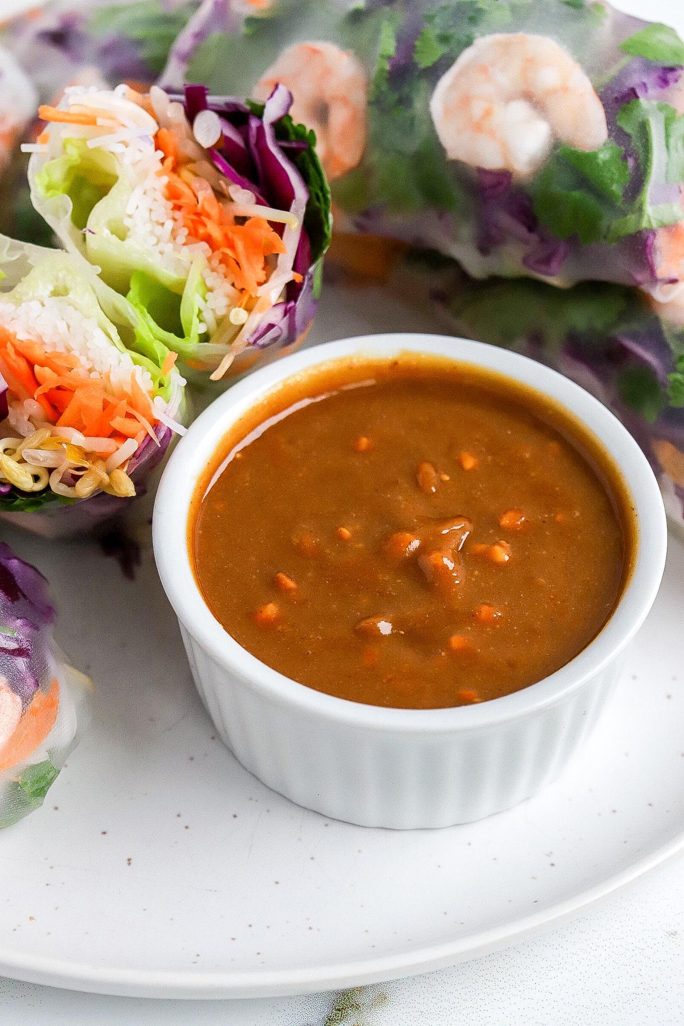 Close up shot of a plate of spring rolls with a peanut dipping sauce