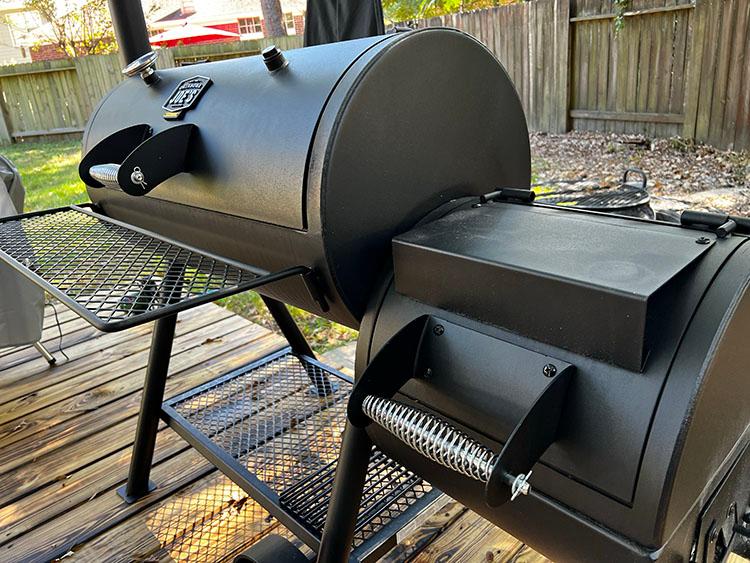 A rustic scene of a smoker with smoke billowing, set in a backyard during golden hour