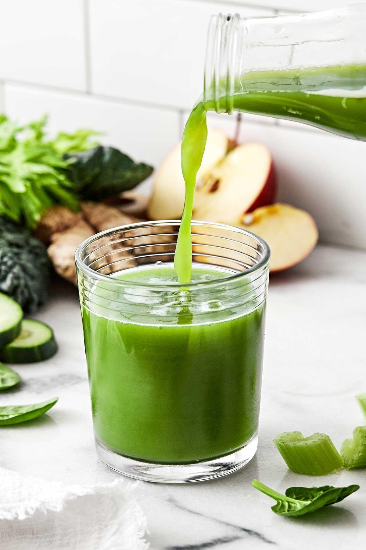 vibrant green smoothie in a glass with fresh ingredients like spinach, kiwi, and ginger