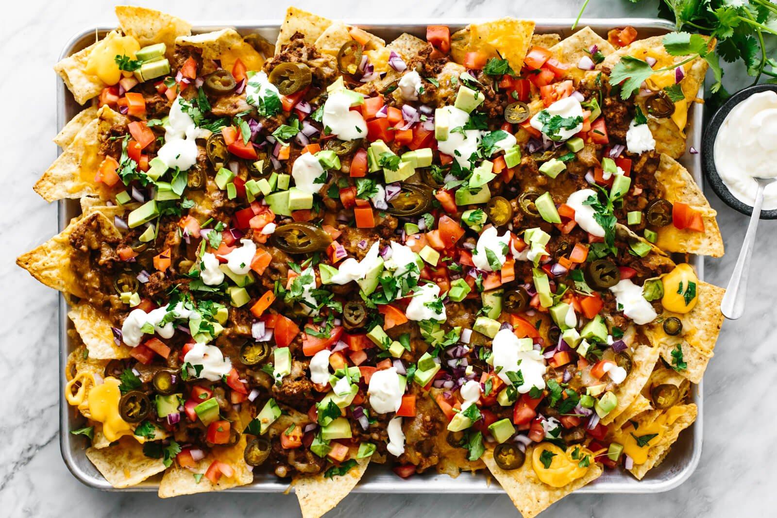 A plate of upscale nachos with all the fixings, showing a variety of toppings and textures.
