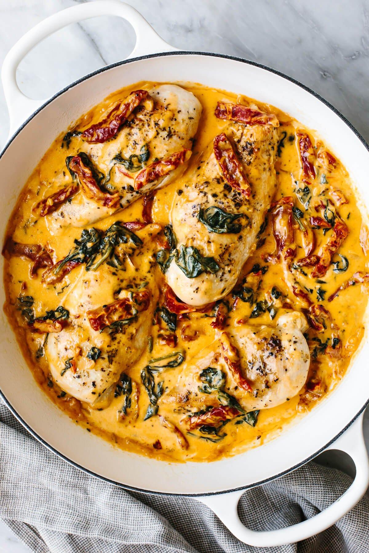 A person serving a plate of creamy Tuscan chicken