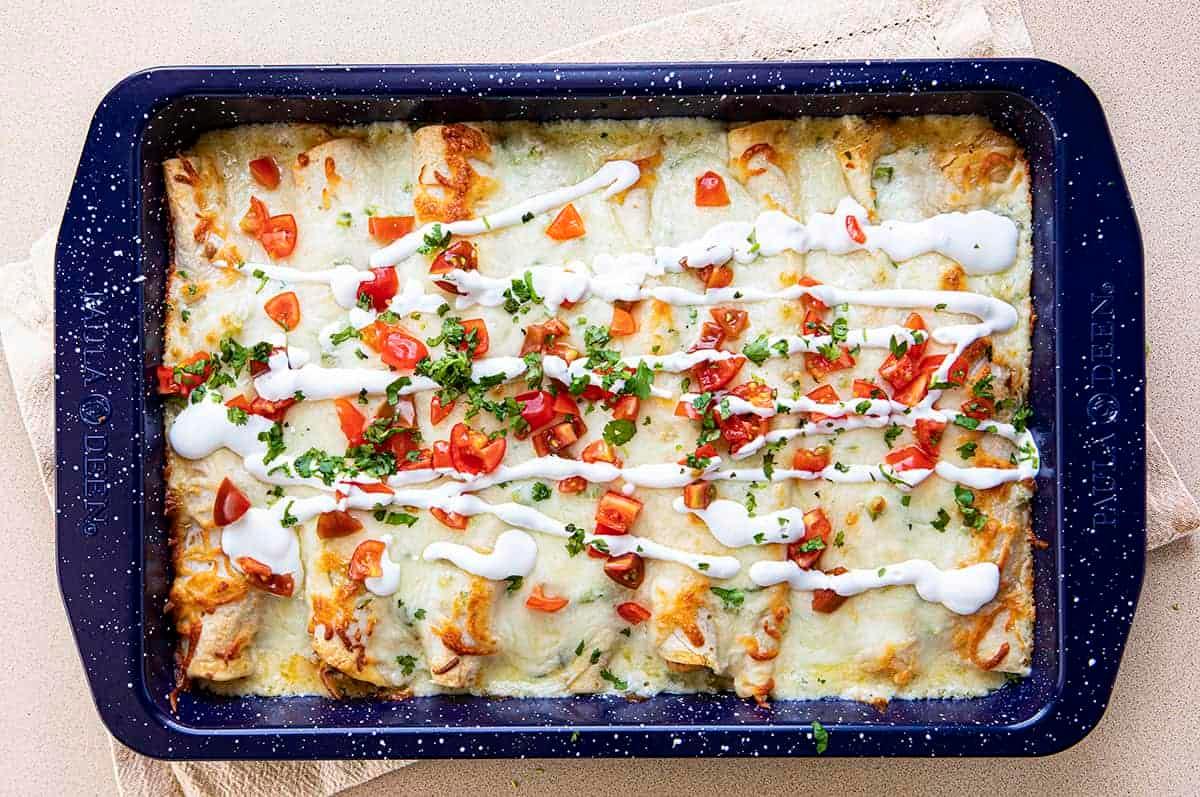 Overhead view of a baking dish filled with seafood enchiladas covered in creamy white sauce.