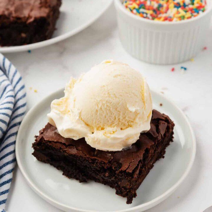A plate of bread pudding brownies with a scoop of vanilla ice cream