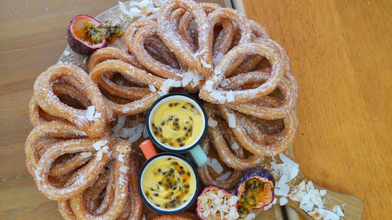 A plate of churros with key lime curd, beautifully styled and set against a tropical background