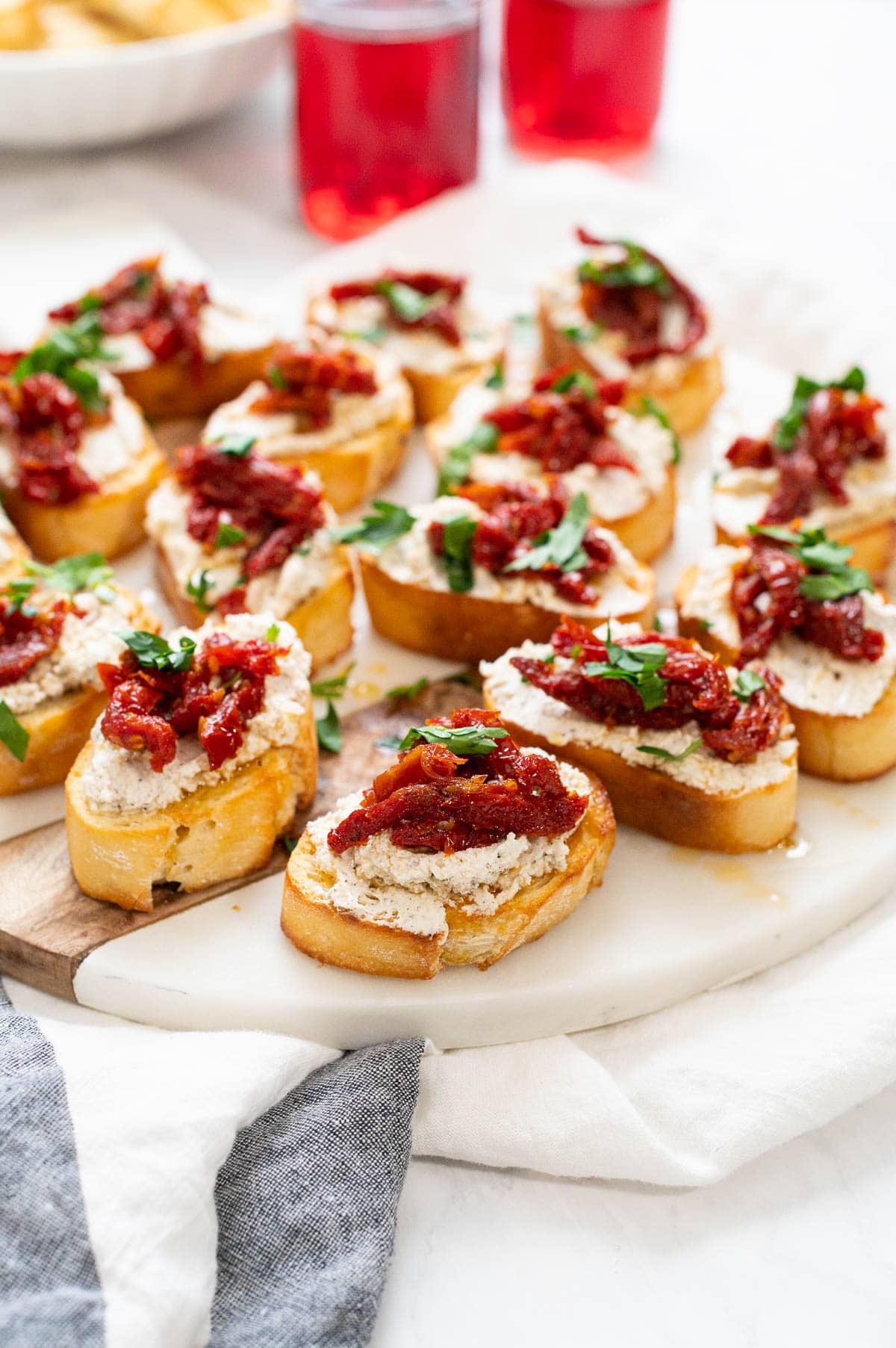 A platter of cashew cheese and sundried tomato crostini garnished with fresh herbs