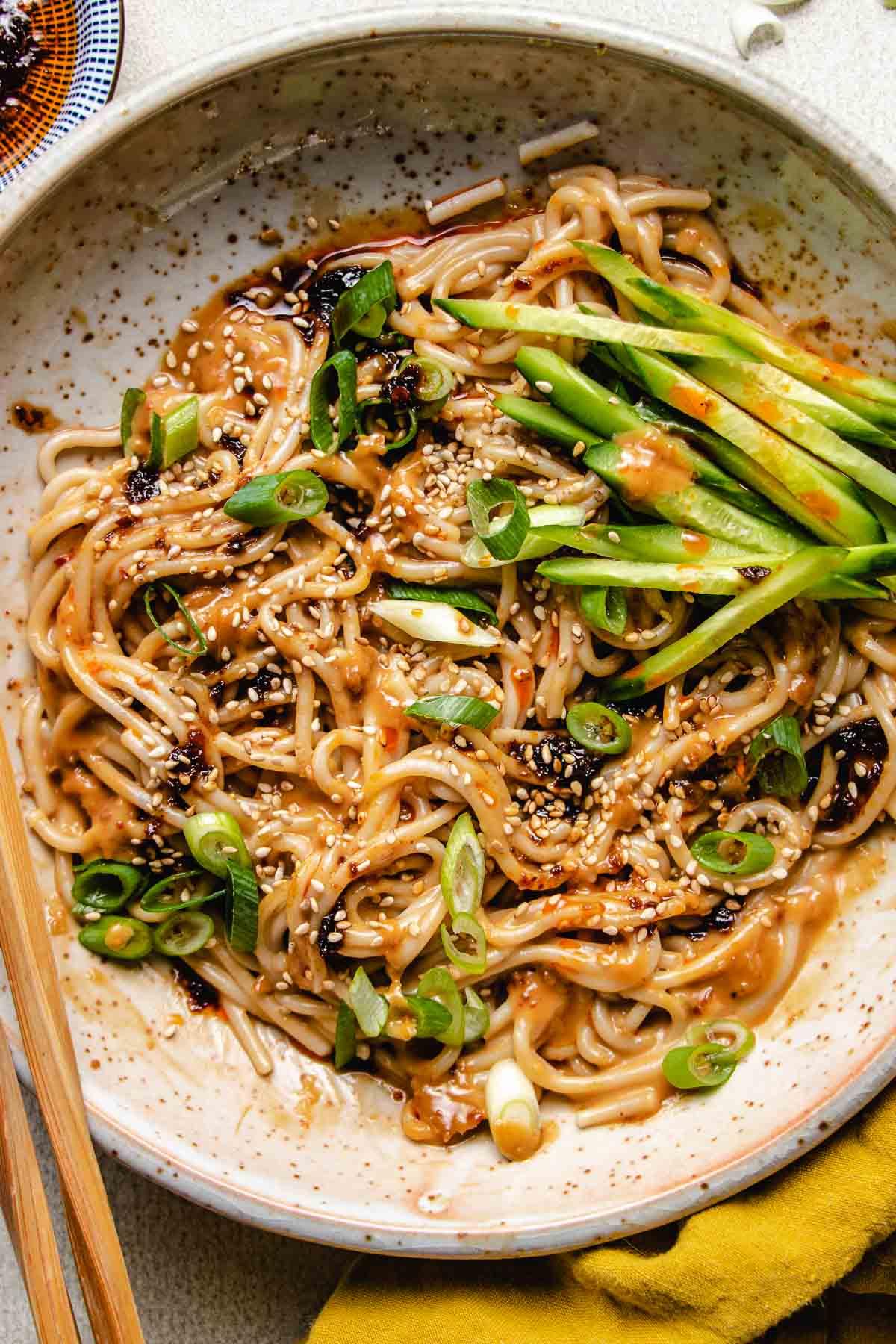 Spicy Peanut Noodles with Shirataki Noodles and Edamame in a bowl, garnished with sesame seeds and peanuts.