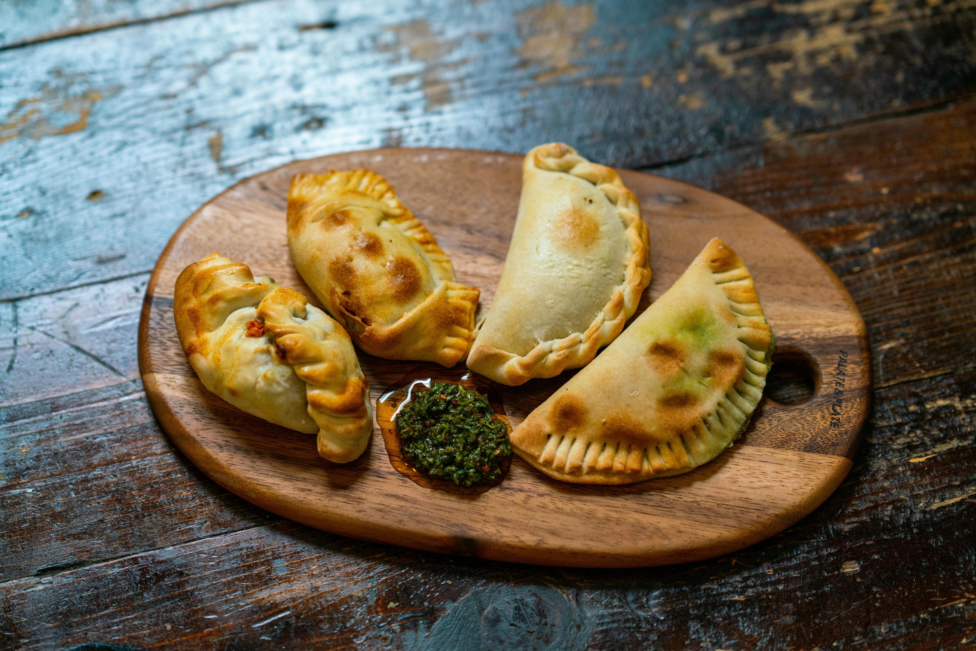 Close-up shot of golden-brown empanadas with a Locro-inspired filling, steam rising