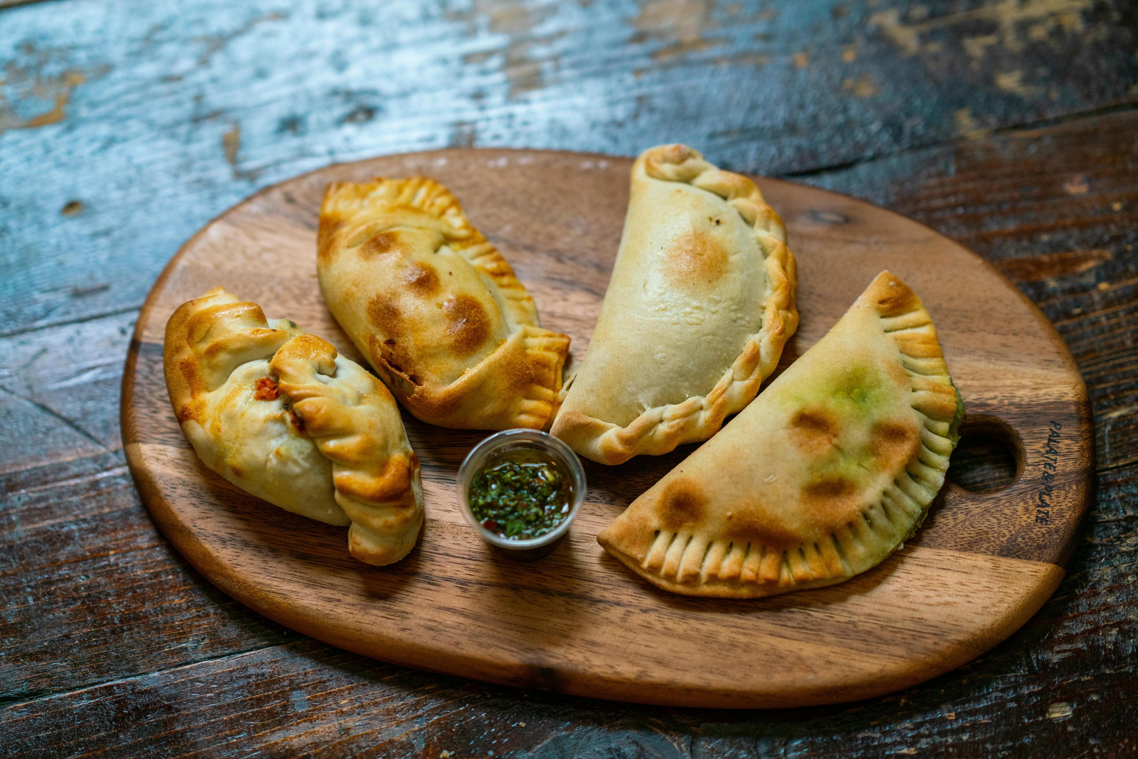 Close-up shot of several Colombian Coffee-Rubbed Steak Empanadas on a rustic wooden board
