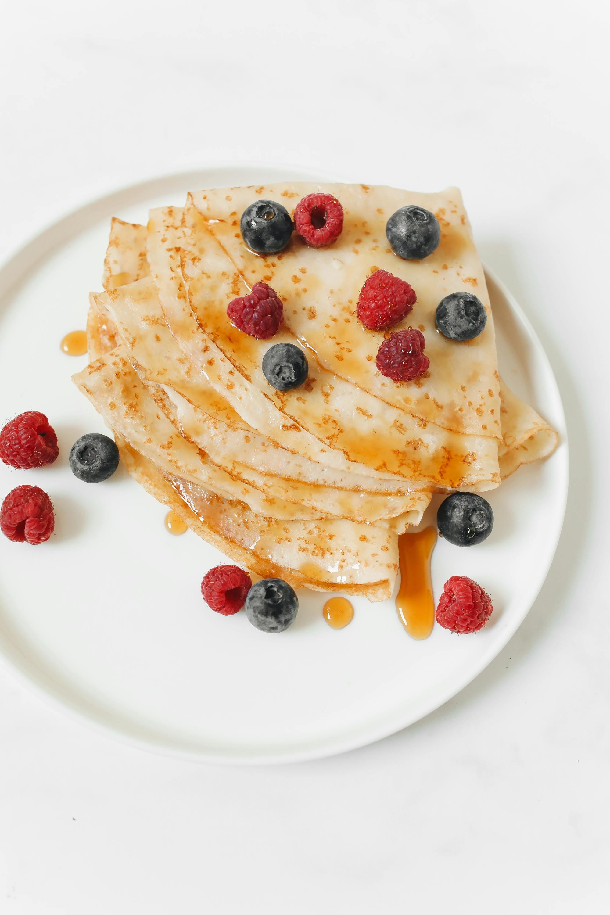 Overhead shot of a plate of champagne crepes with berries, garnished with mint leaves