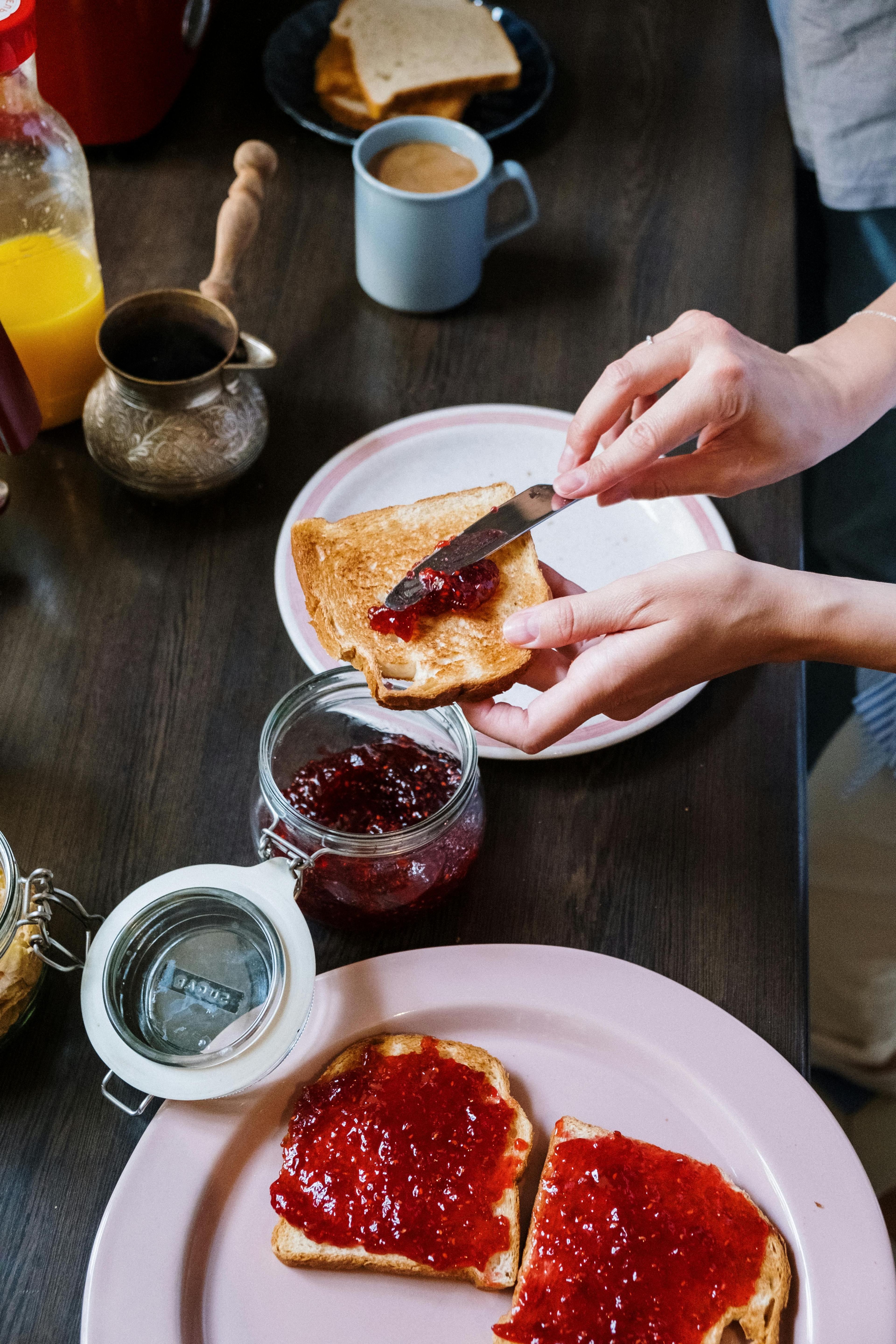 A person spreading lingonberry jam on toast