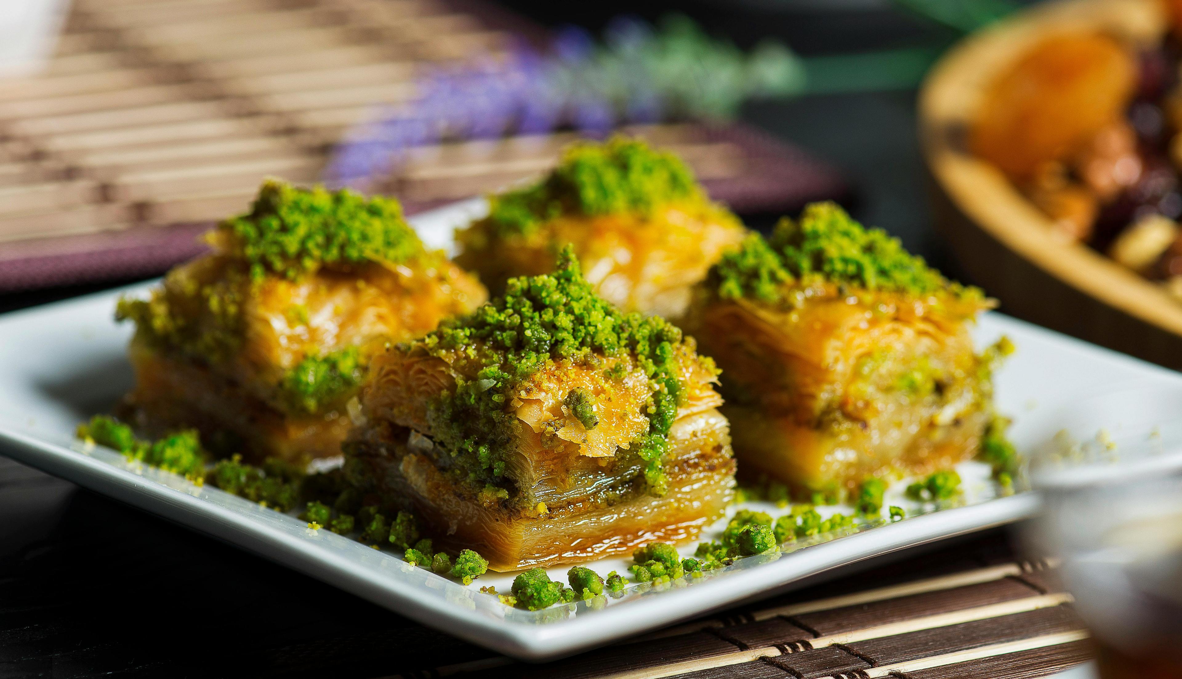 Close-up shot of baklava with a glossy hummus glaze, drizzled with honey, and garnished with pistachios