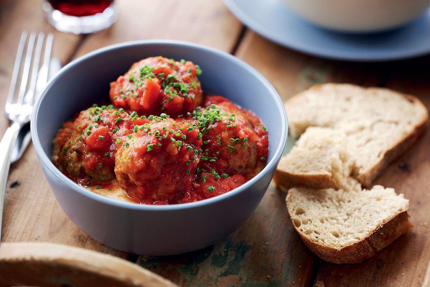 Close up of individual köttbullar in creamy tomato sauce, garnished with parsley