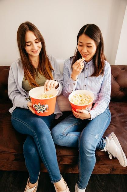 Two people eating lobster butter popcorn on a couch