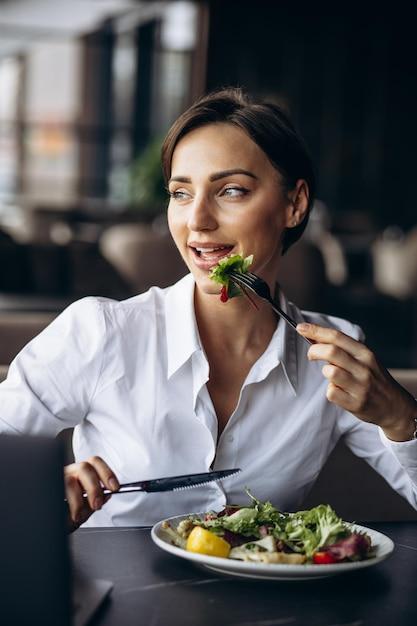 woman happily eating curried chickpea salad at an outdoor cafe