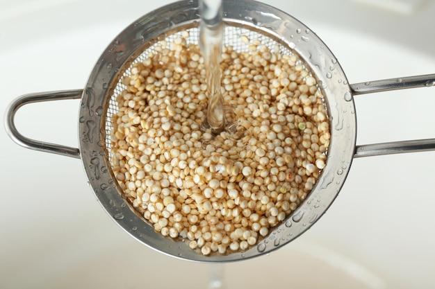 a close-up shot of quinoa grains being rinsed in a sieve