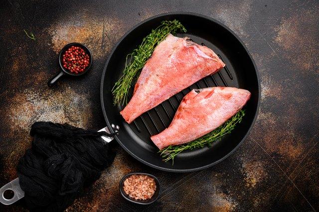 A person grilling fish fillets on a grill pan