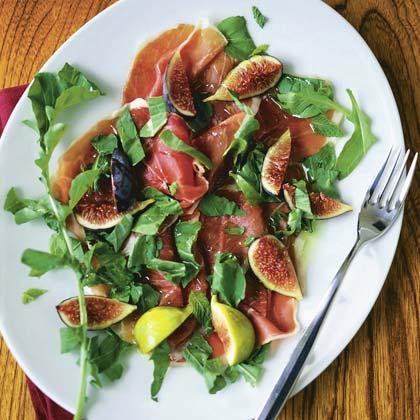 Prosciutto and Fig Eggs Florentine being served on a plate with a side of fresh fruit