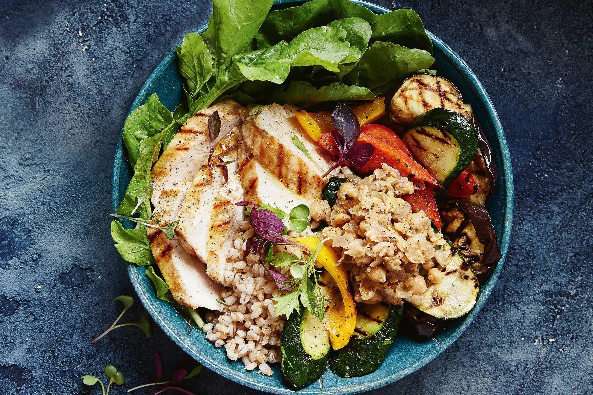 Close-up shot of a bowl of barley with roasted chicken and potatoes