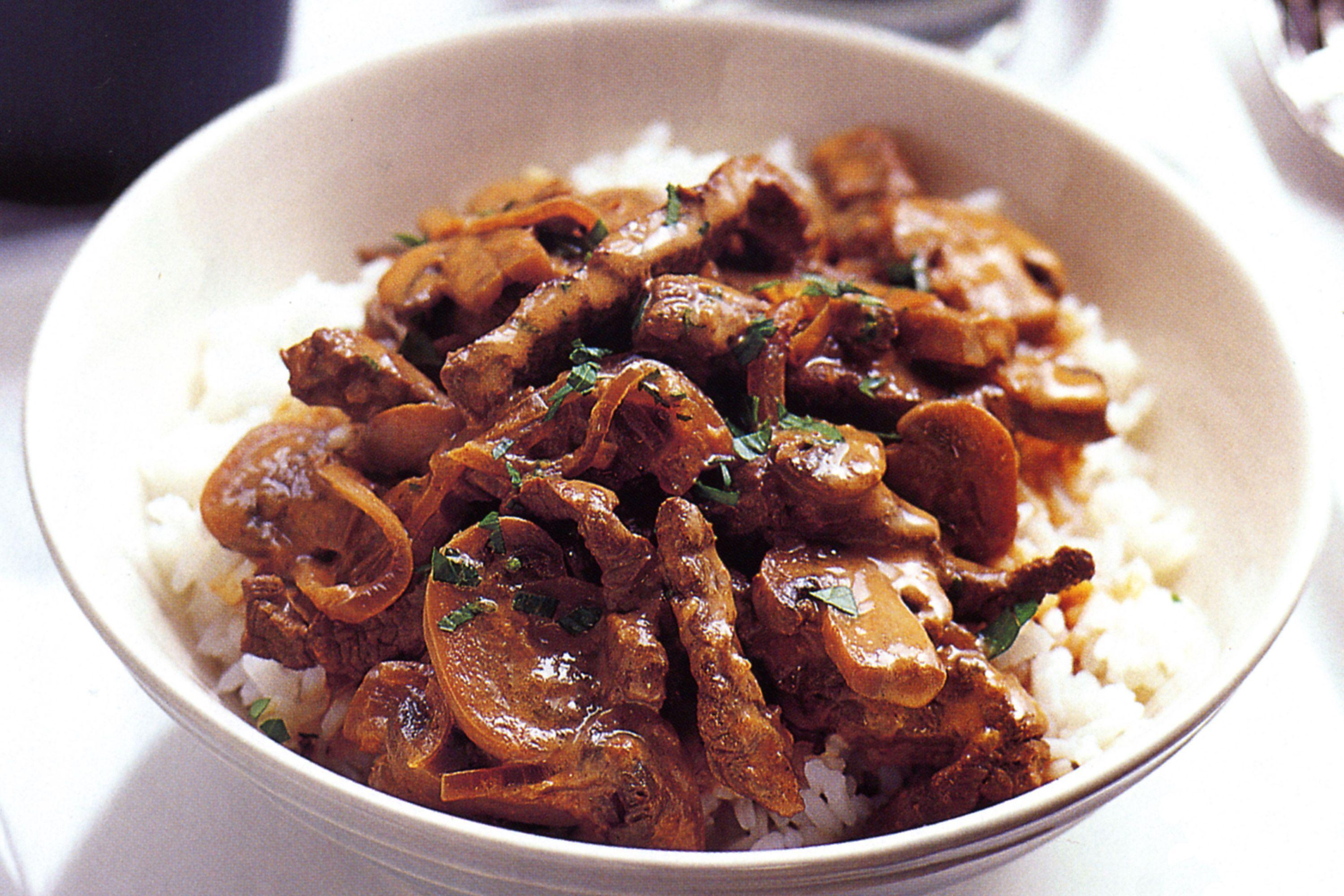 Beef Stroganoff served over rice in a rustic bowl