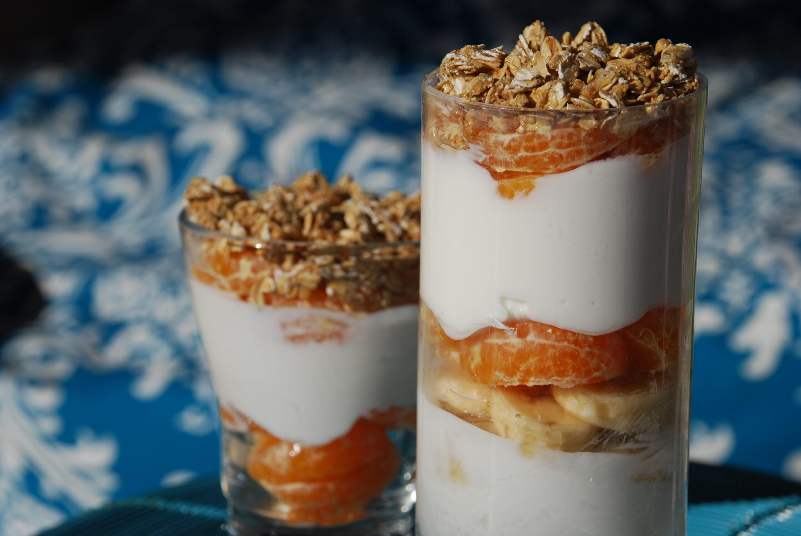 Close-up shot of a tangerine and yogurt parfait with a spoon.