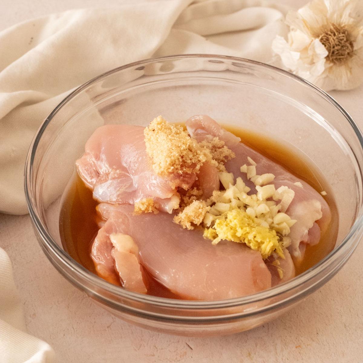 Chicken marinating in a bowl with Hawaiian-inspired ingredients