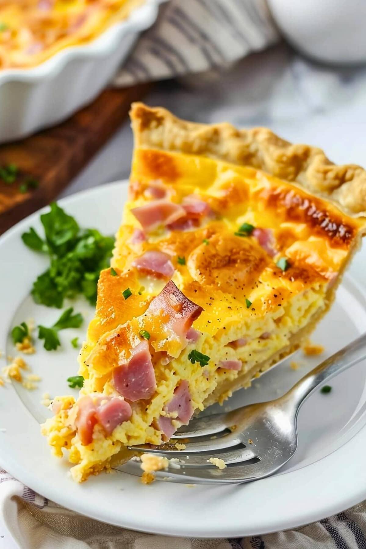 a person slicing into a ham and cheddar quiche bite, revealing the layers of flaky crust, savory ham, and melted cheese.