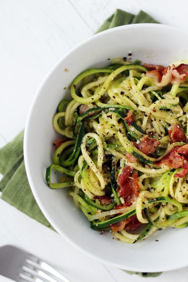 Close-up shot of zucchini noodles with crispy bacon and caramelized onions