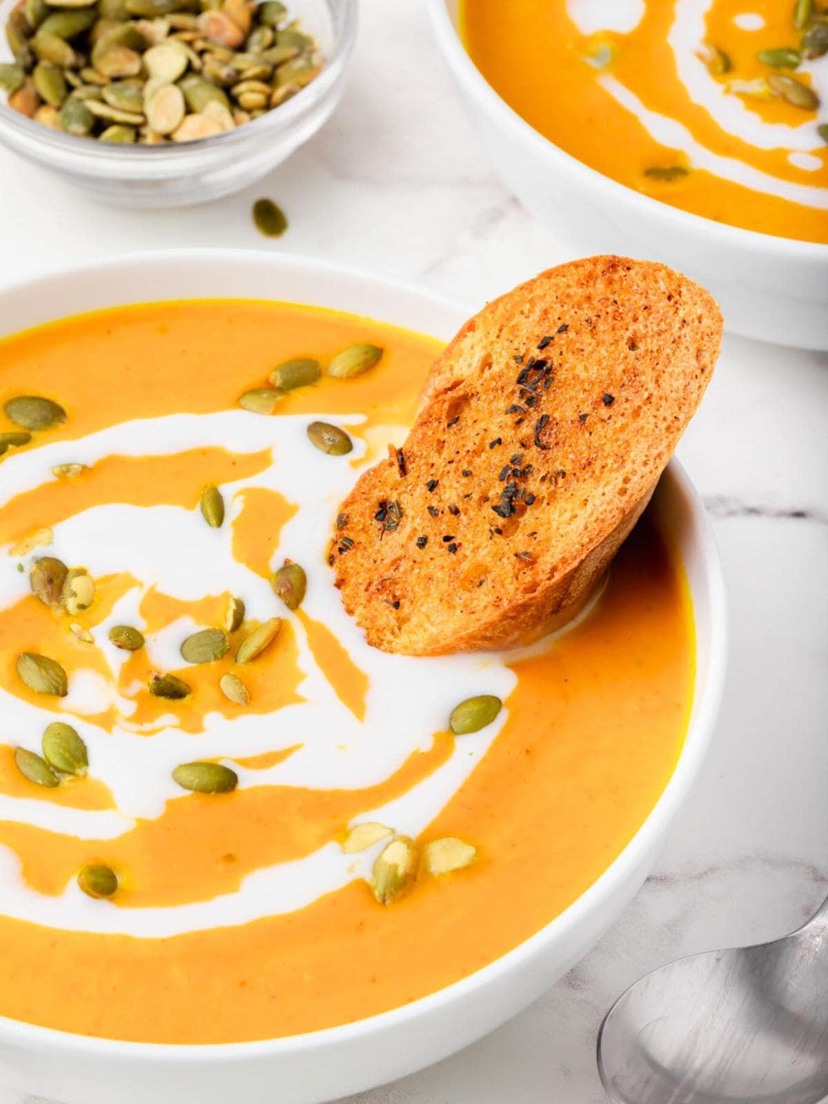 A rustic bowl of creamy pumpkin soup garnished with pumpkin seeds and a swirl of cream