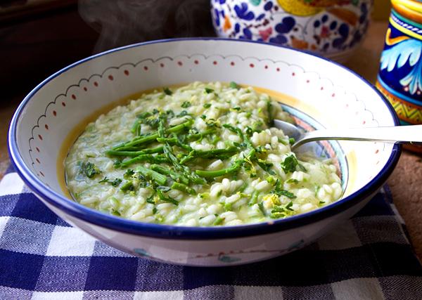 A beautifully plated bowl of Asparagus Risotto with Wild Rice, garnished with fresh herbs and parmesan cheese, set on a rustic wooden table.