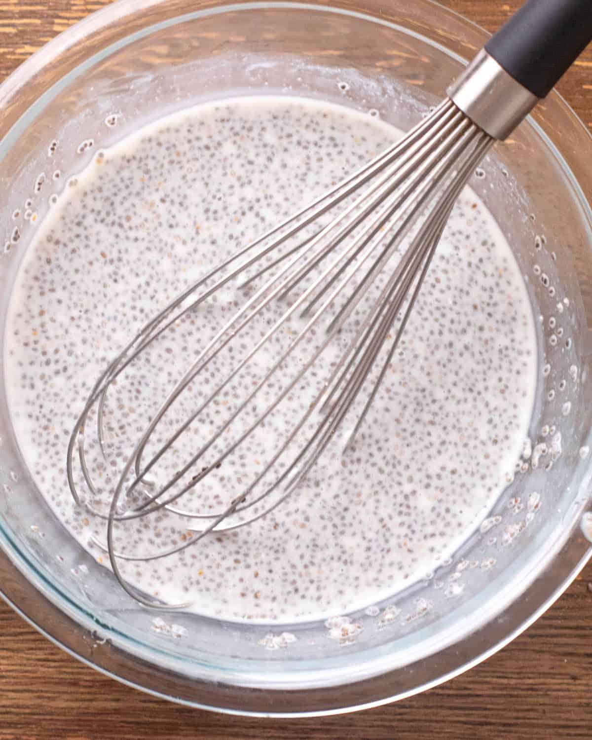 Close-up of chia seeds being mixed into milk with a whisk