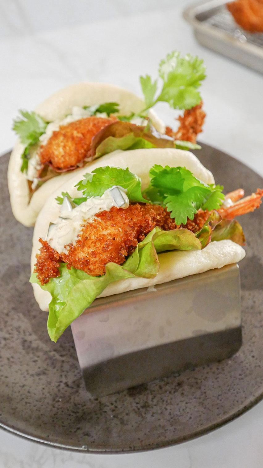 Crispy shrimp and avocado tempura on a white plate, garnished with lime wedges